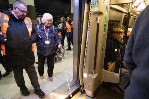 Image showing train guard guiding female passenger onto train, with step free access